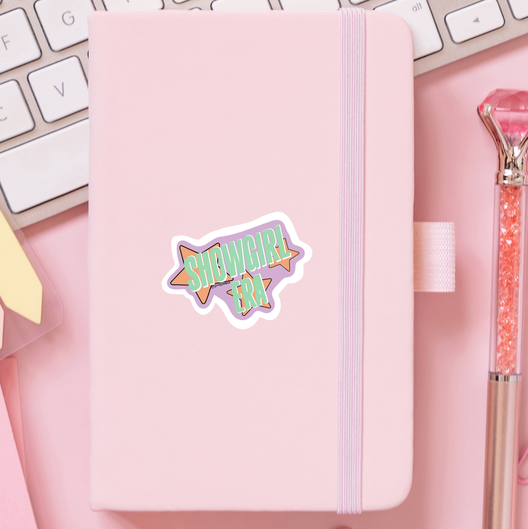 Showgirl Era sticker on a pink notebook.