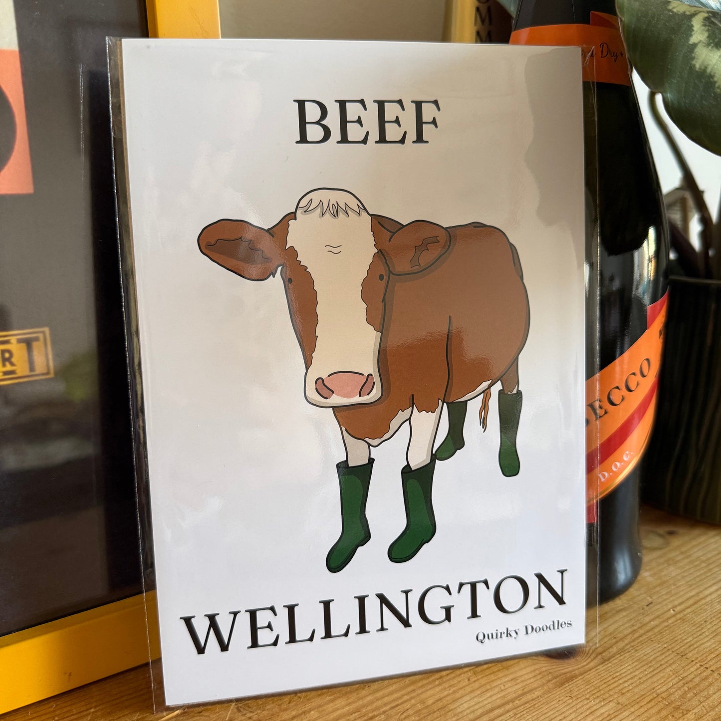 Print titled 'Beef Wellington' with a cow illustration on a wooden surface.