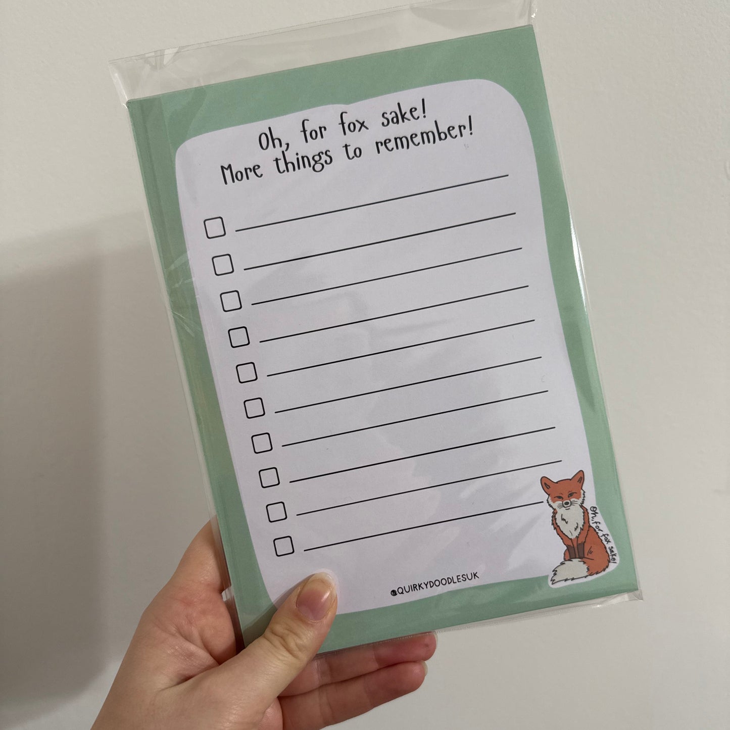 Hand holding a notepad with checkboxes and text on a white background