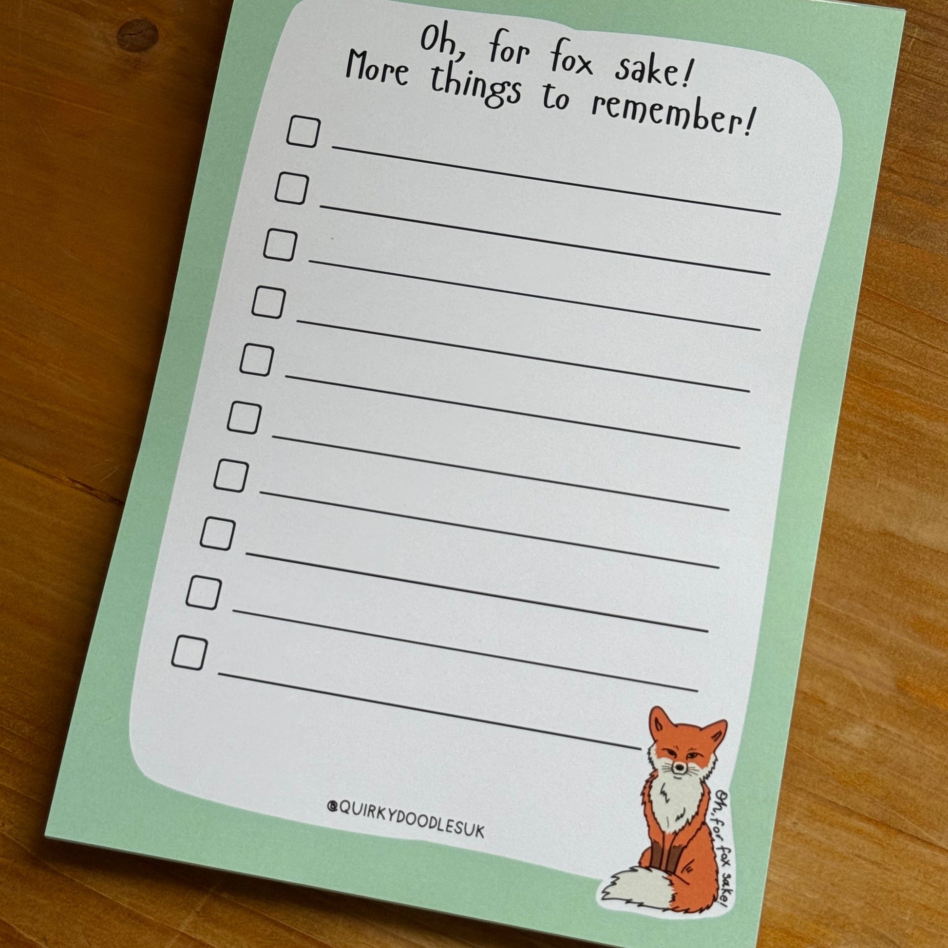 Notepad with fox illustration and text on a wooden surface