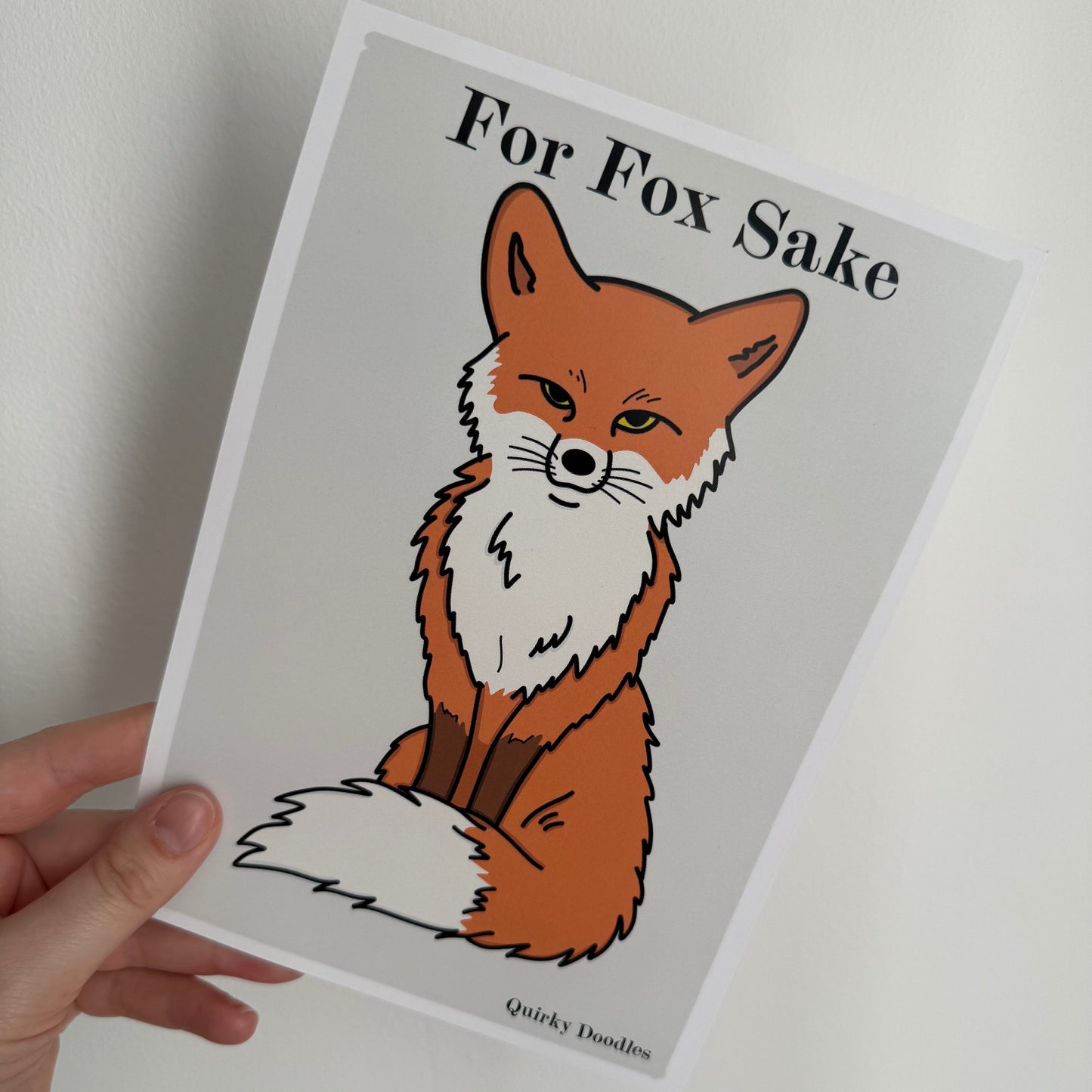 Card with a fox illustration and text 'For Fox Sake' held by a hand on a white background