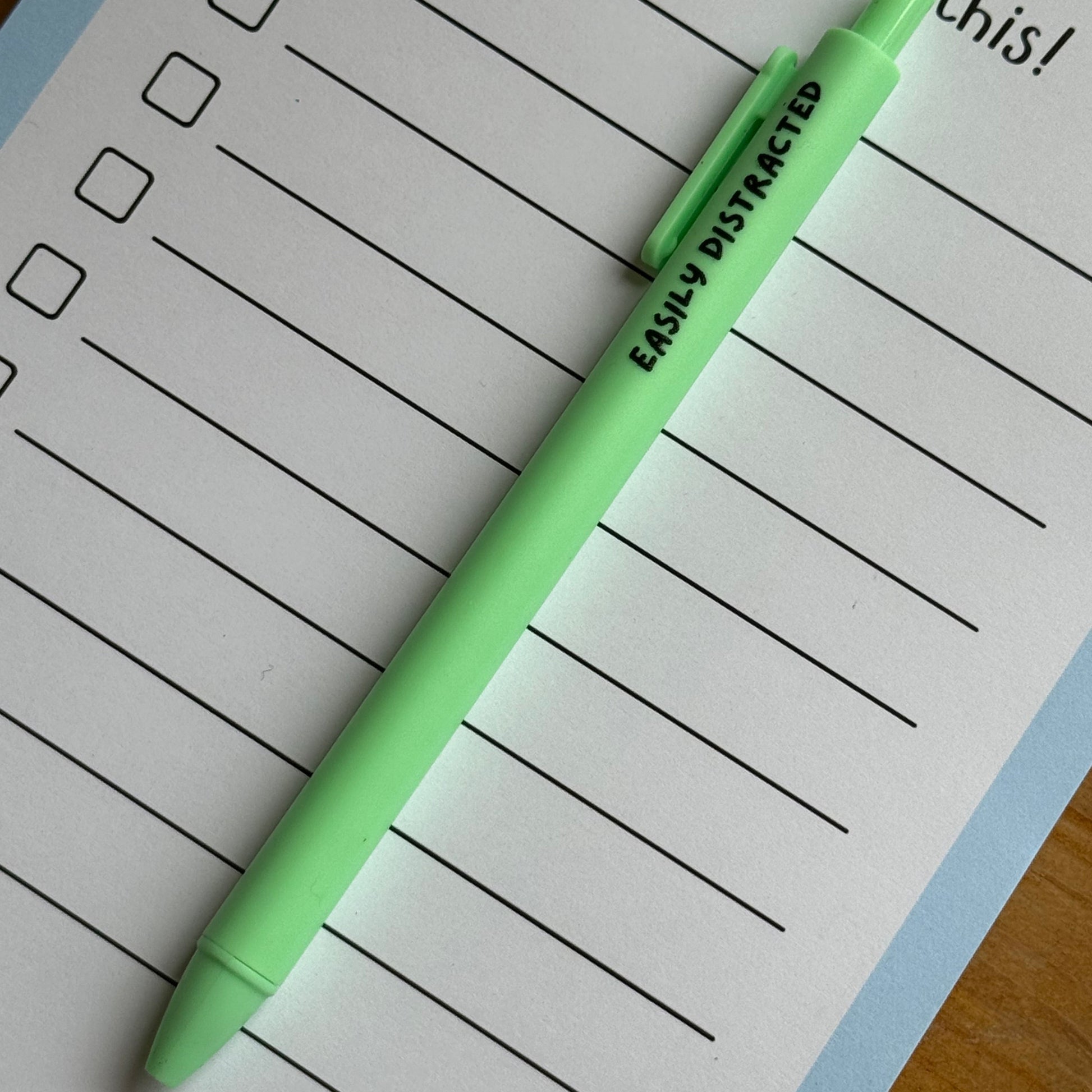 Green pen on a lined notepad with a cartoon goose illustration