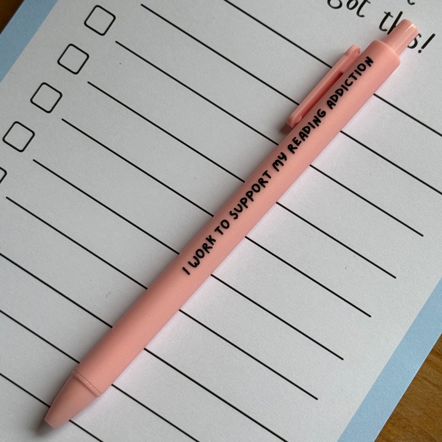 Pink pen with text on a lined notepad