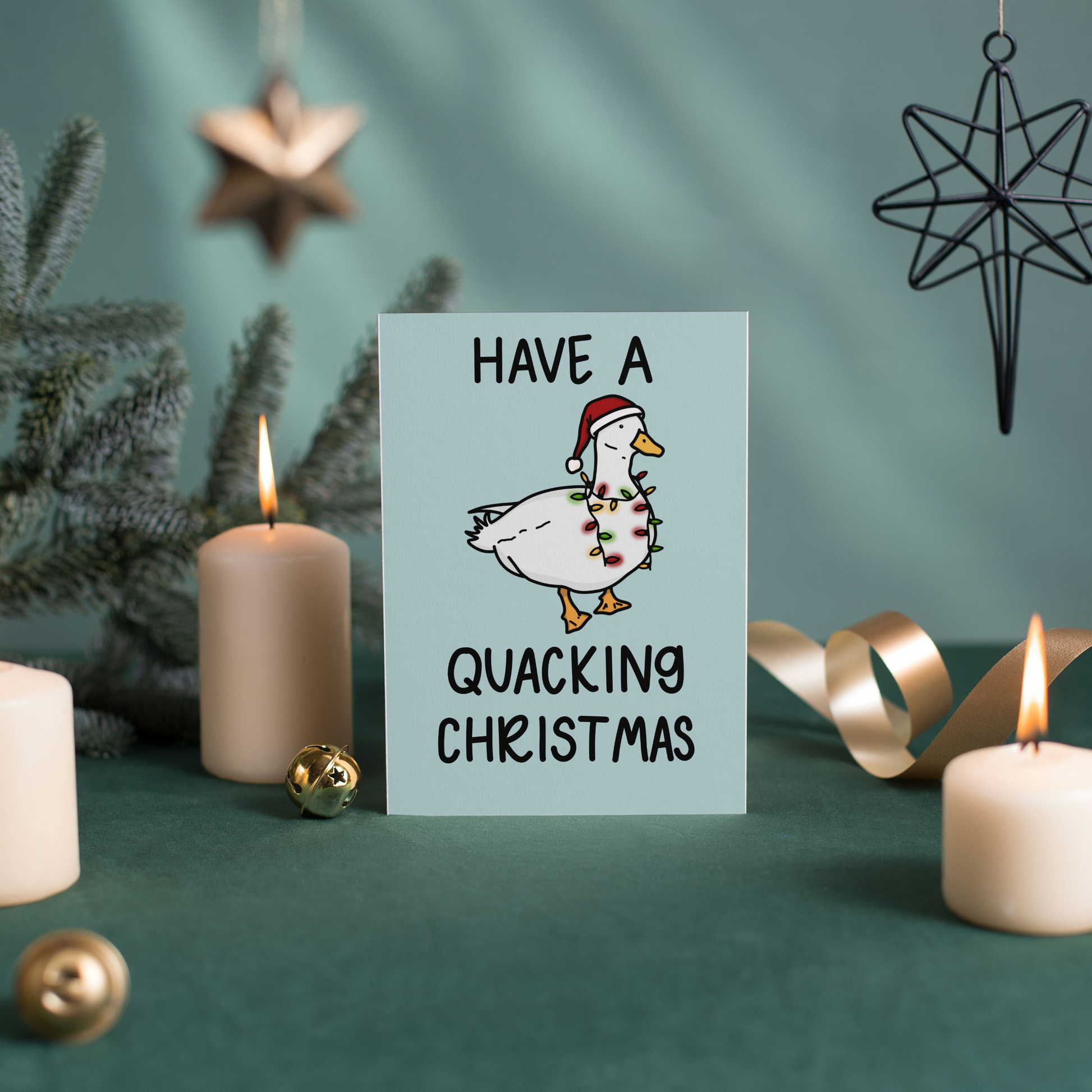 Card with 'Have a Quacking Christmas' text and duck illustration surrounded by candles and decorations on a green background.