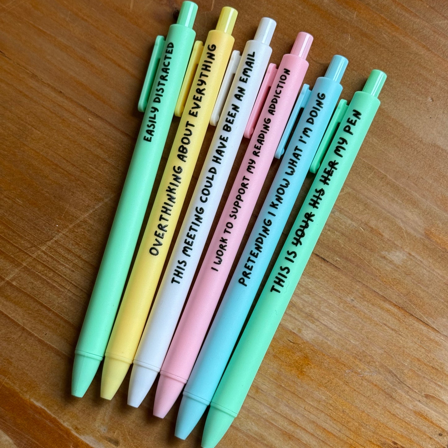 Set of colorful pens with text on a wooden surface