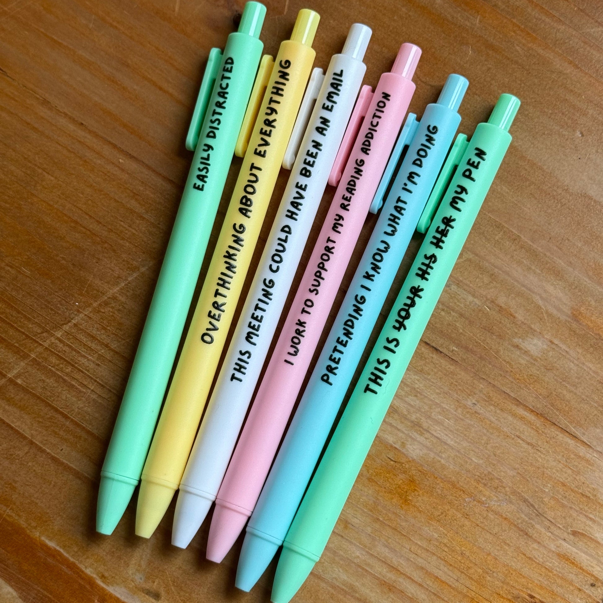 Set of colorful pens with text on a wooden surface