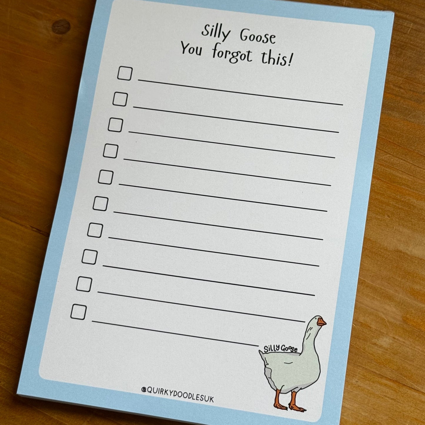 Notebook with a cartoon goose illustration and text on a wooden surface