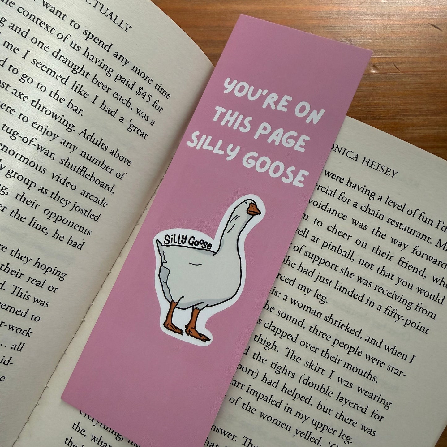 Pink bookmark with a goose illustration and text on a book page