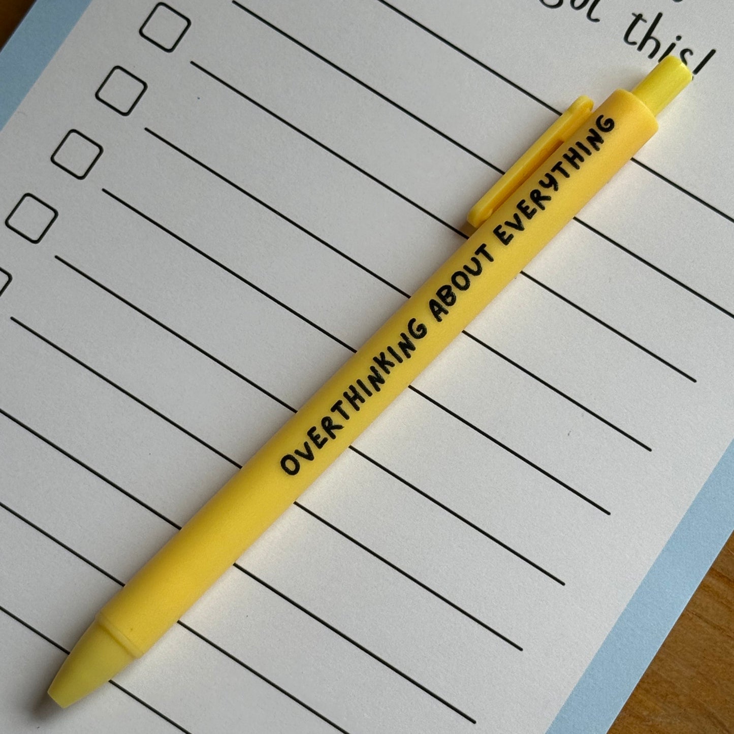 Yellow pen with text on a lined notepad