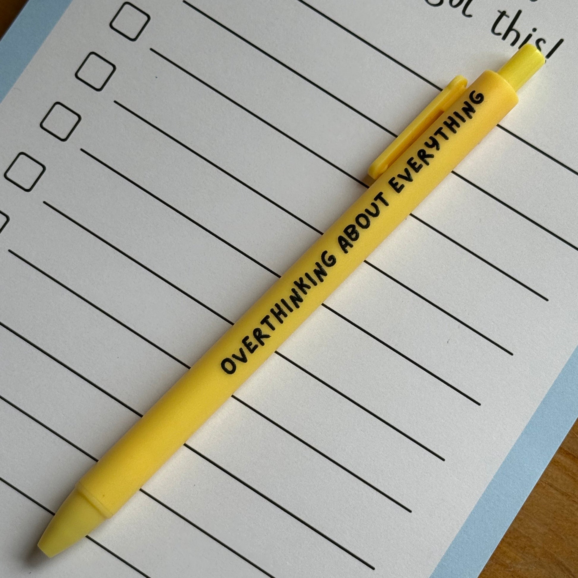 Yellow pen with text on a lined notepad