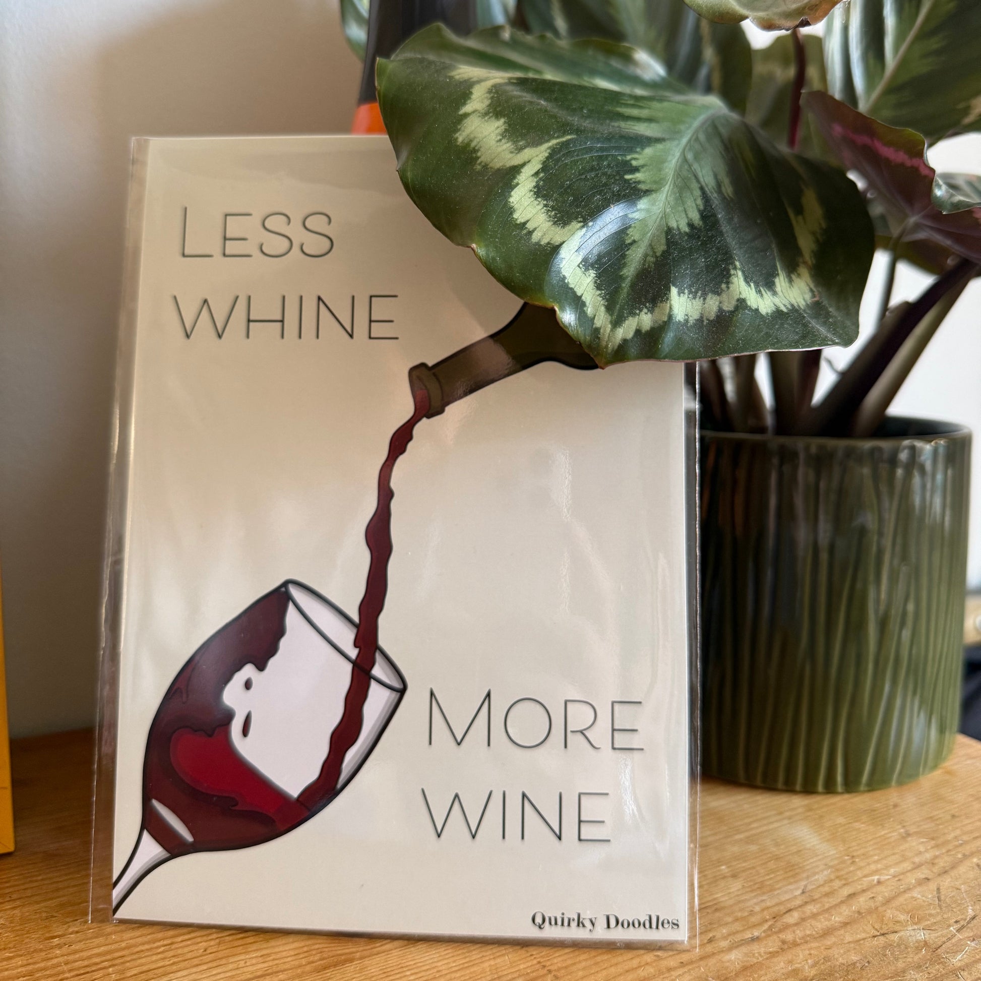 print with humorous wine-themed text and graphics on a wooden surface.